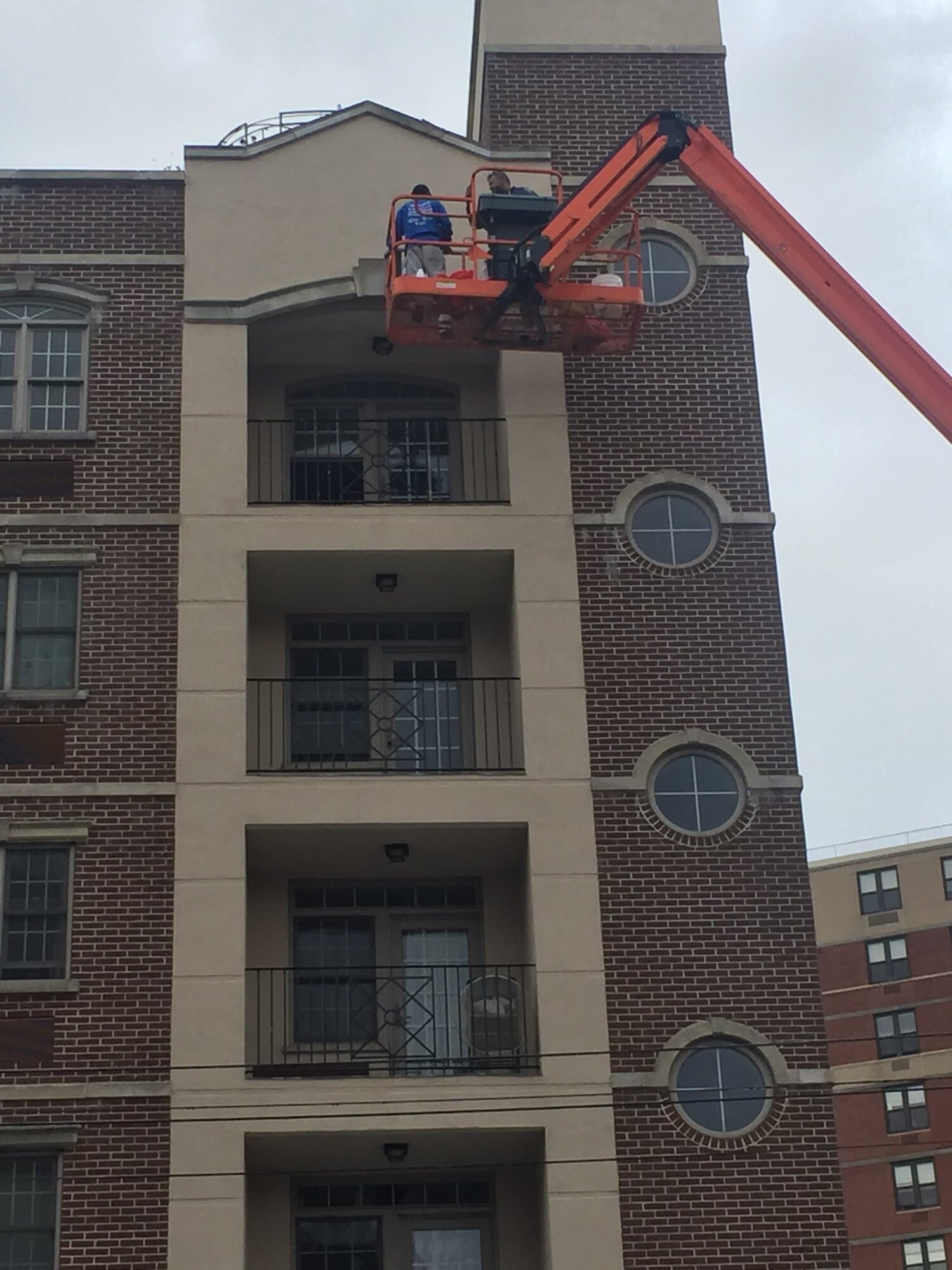 Licensed structural engineers on a boom lift inspecting a multi-story building exterior in Newark, New Jersey
